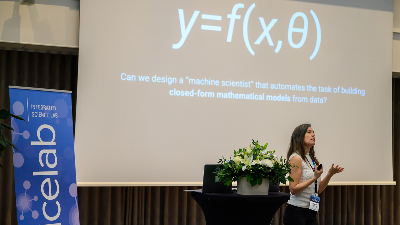 Marta Sales Pardo presents next to flowers and a large screen