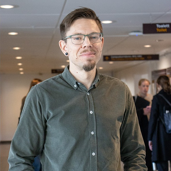 En man i grön skjorta står på en flygplats.