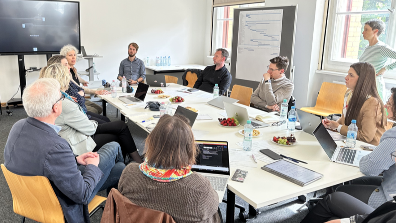 En grupp människor som sitter runt ett bord med bärbara datorer.