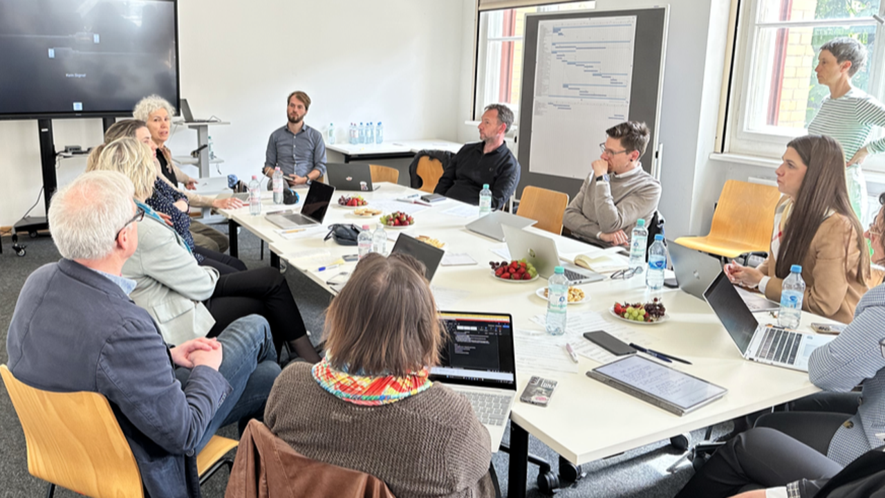 En grupp människor som sitter runt ett bord med bärbara datorer.