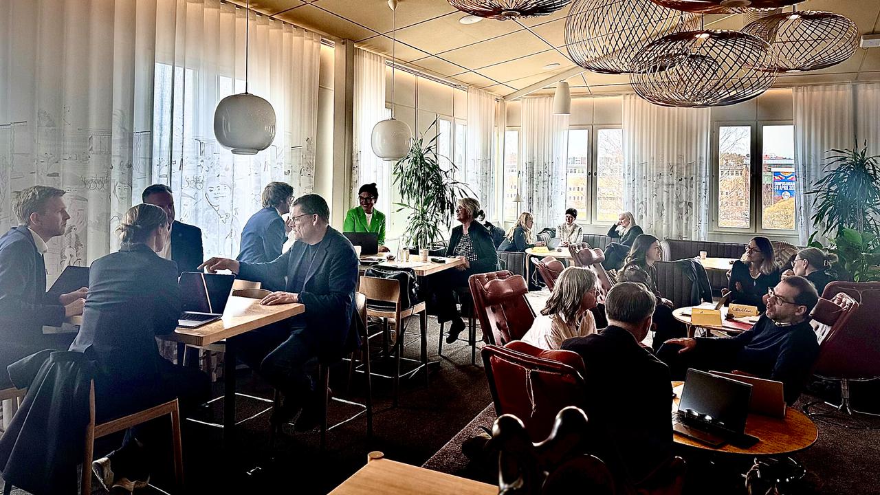 grupp av människor diskuterar vid olika bord