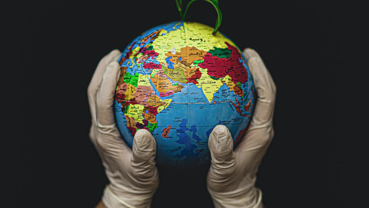 Två händer som håller i en liten jordglob med en växt som växer ut ur den.