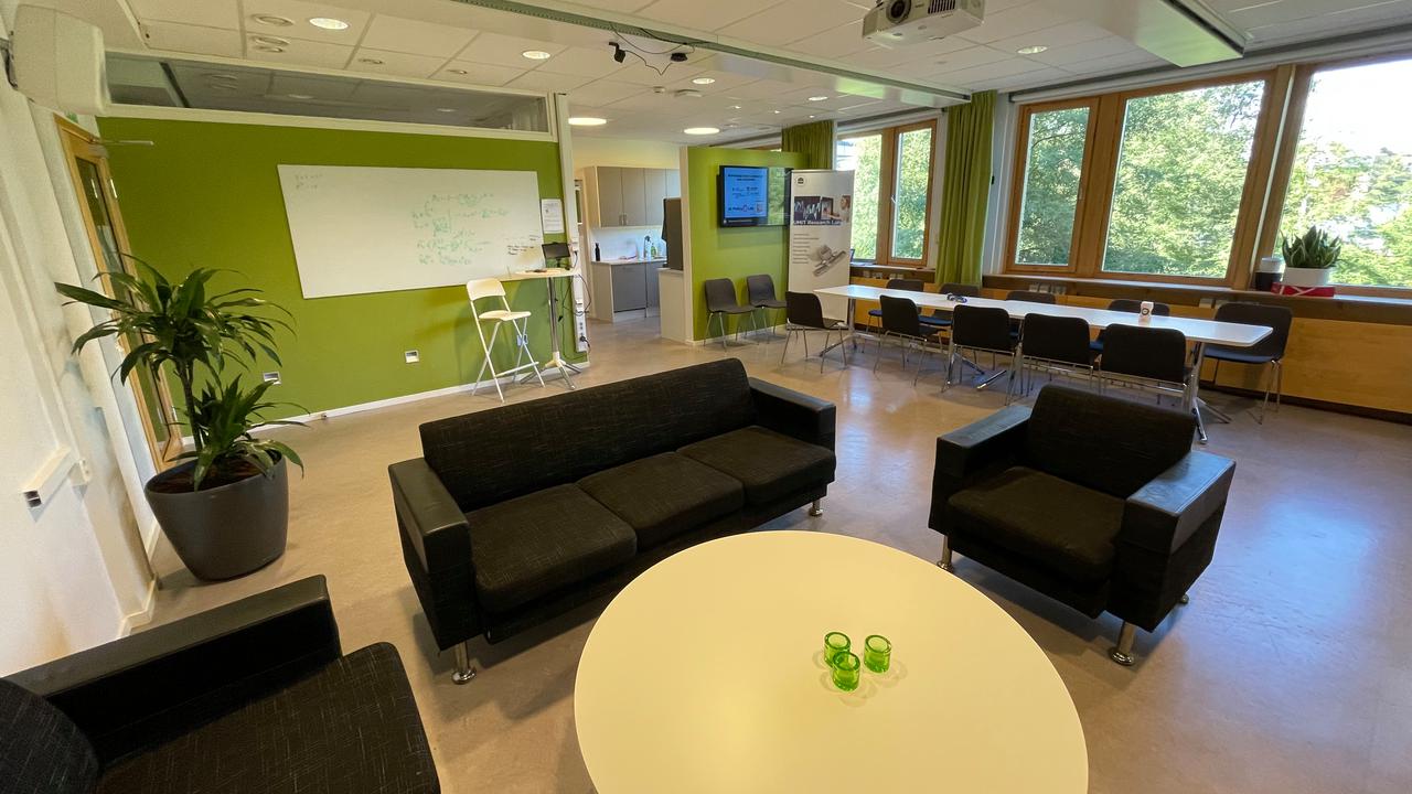 Ett rum med soffor, stolar, bord och en projektorduk.