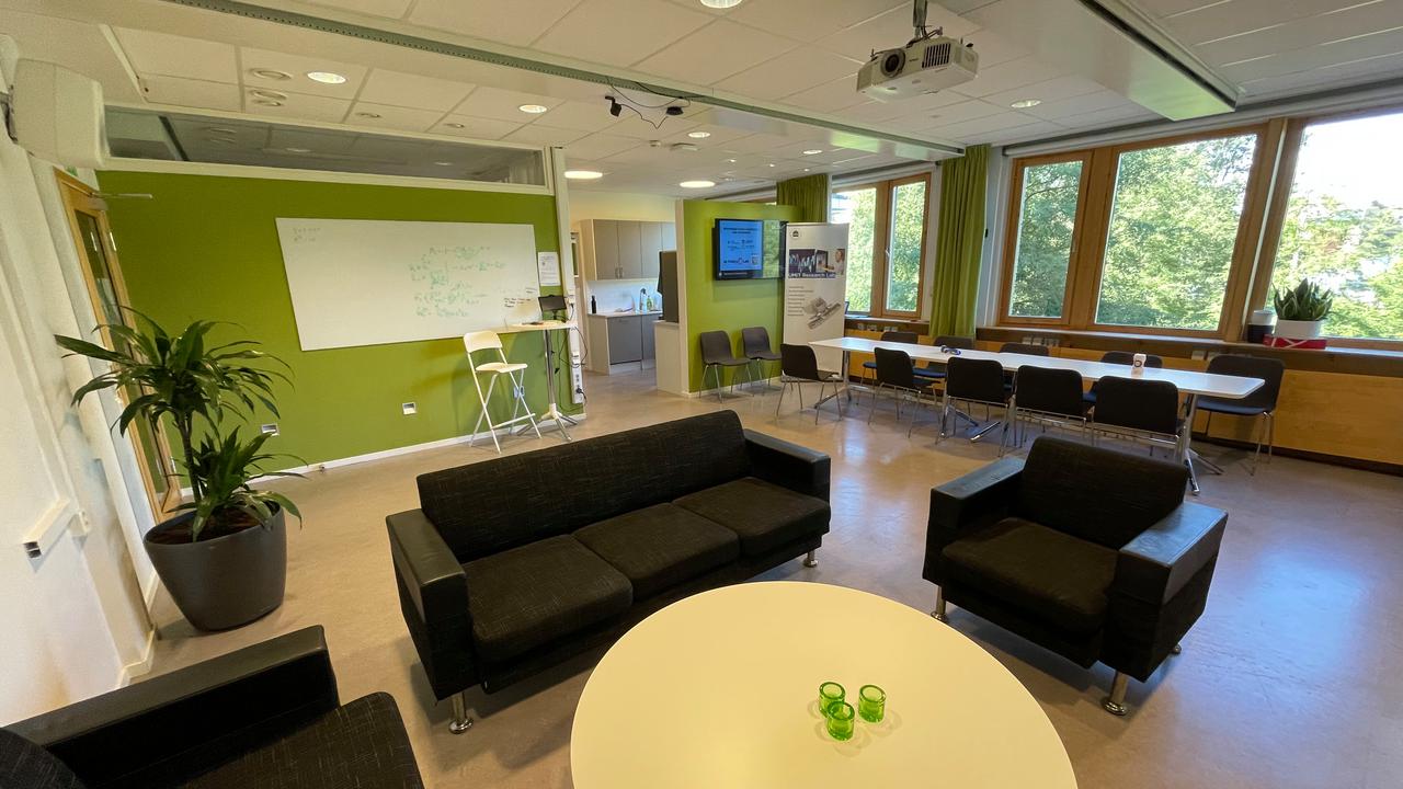 Ett rum med soffor, stolar, bord och en projektorduk.