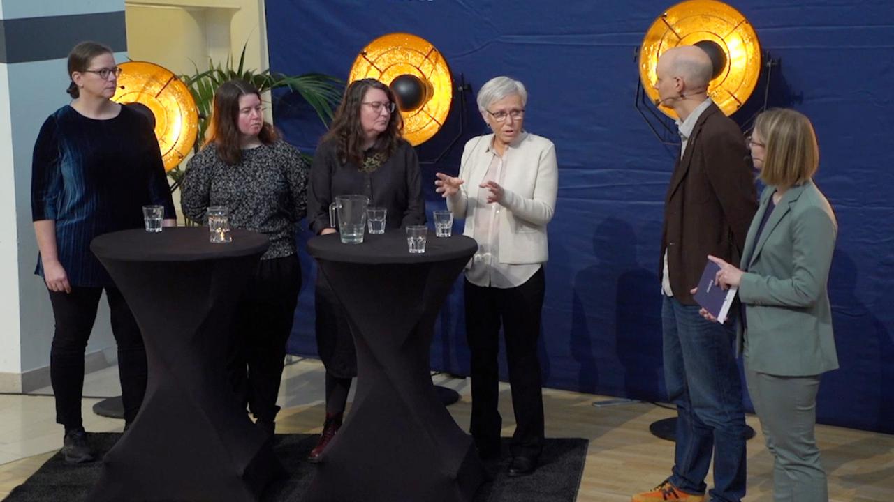 A panel discussion with two moderators and four participants.