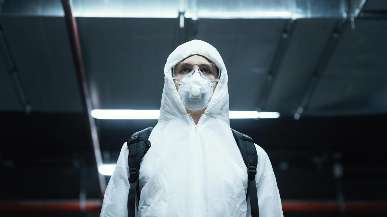 En person iförd skyddskläder och andningsmask.