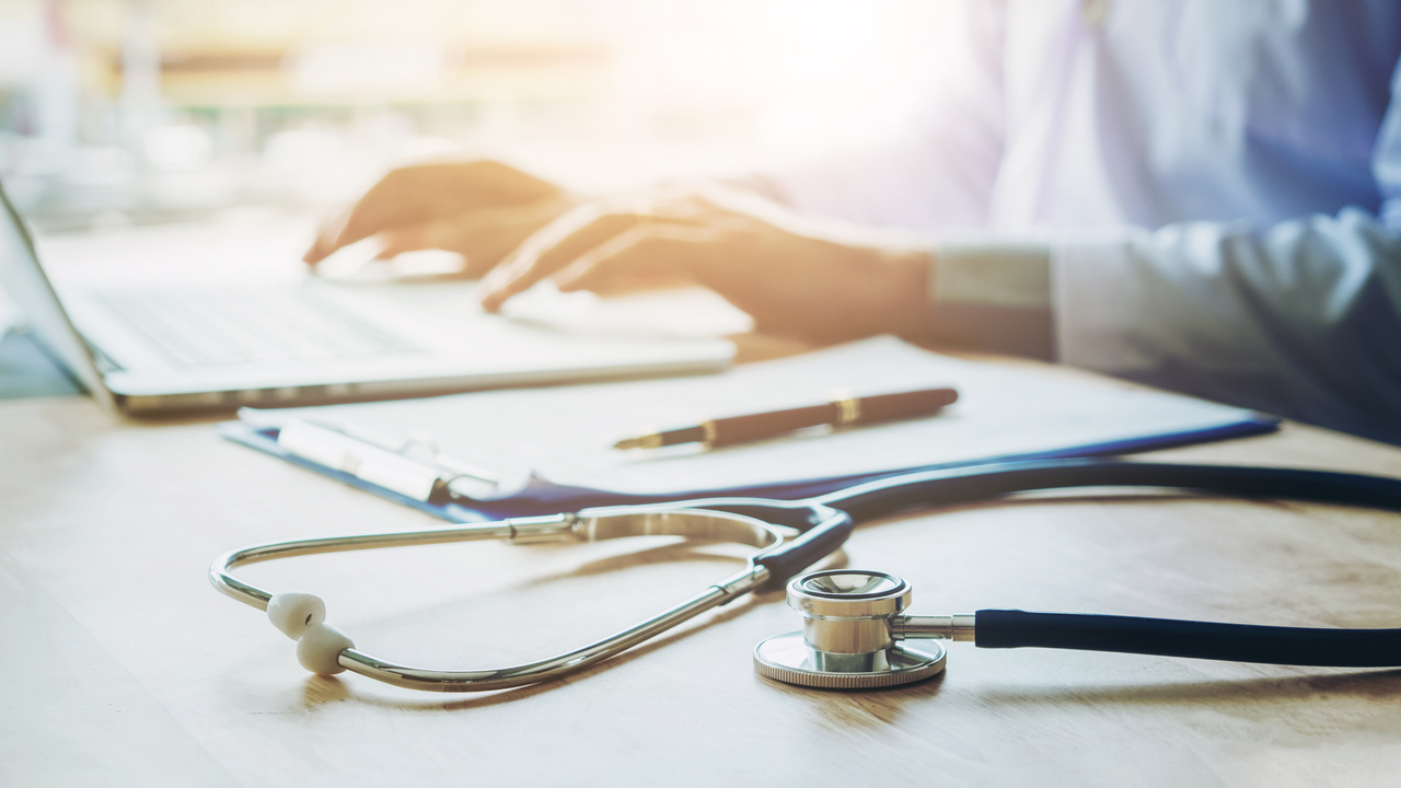 Läkare skriver på en laptop. Fokus på stetoskop.