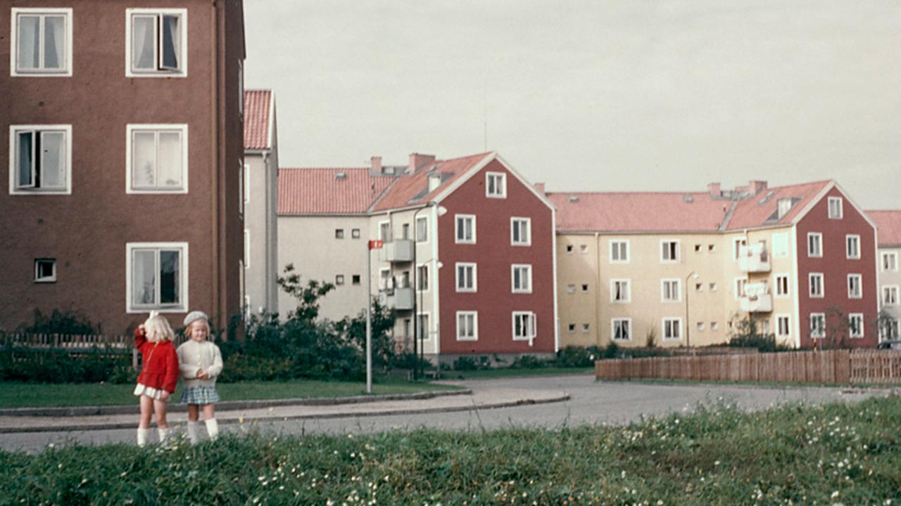 Två flickor står framför en rad med hus.