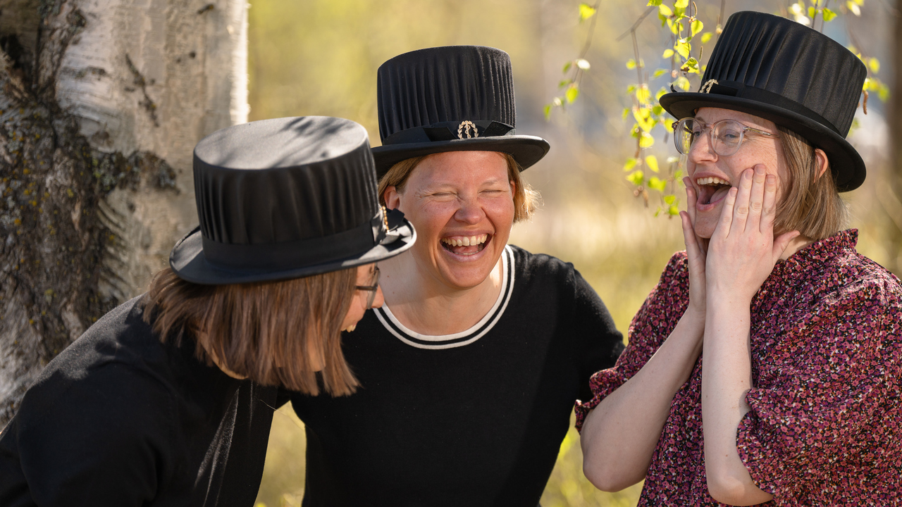 Tre systrar står bredvid varandra och skrattar.