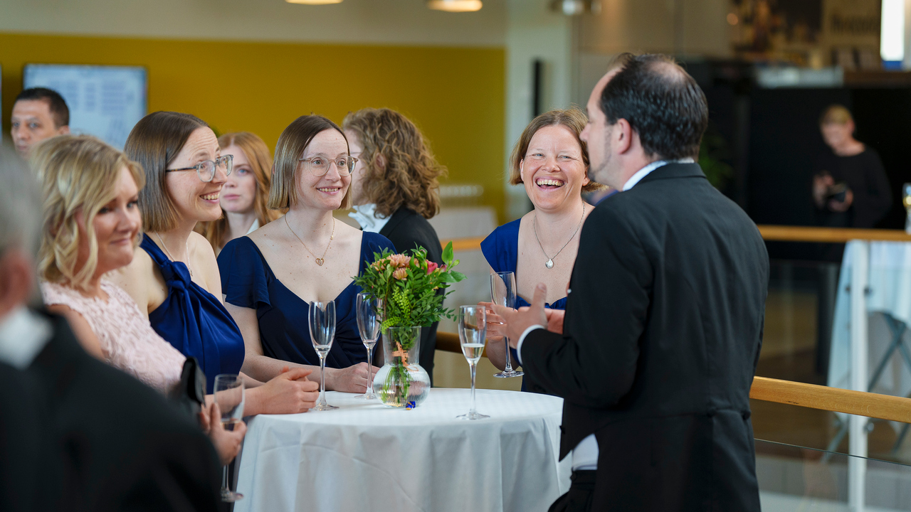 Personer står runt ett bord och pratar och skrattar