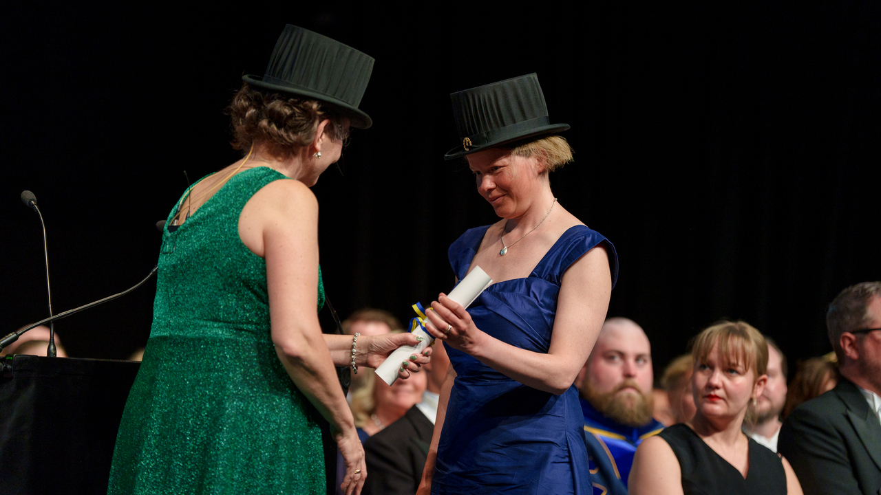 Kvinna ger annan kvinna ett diplom