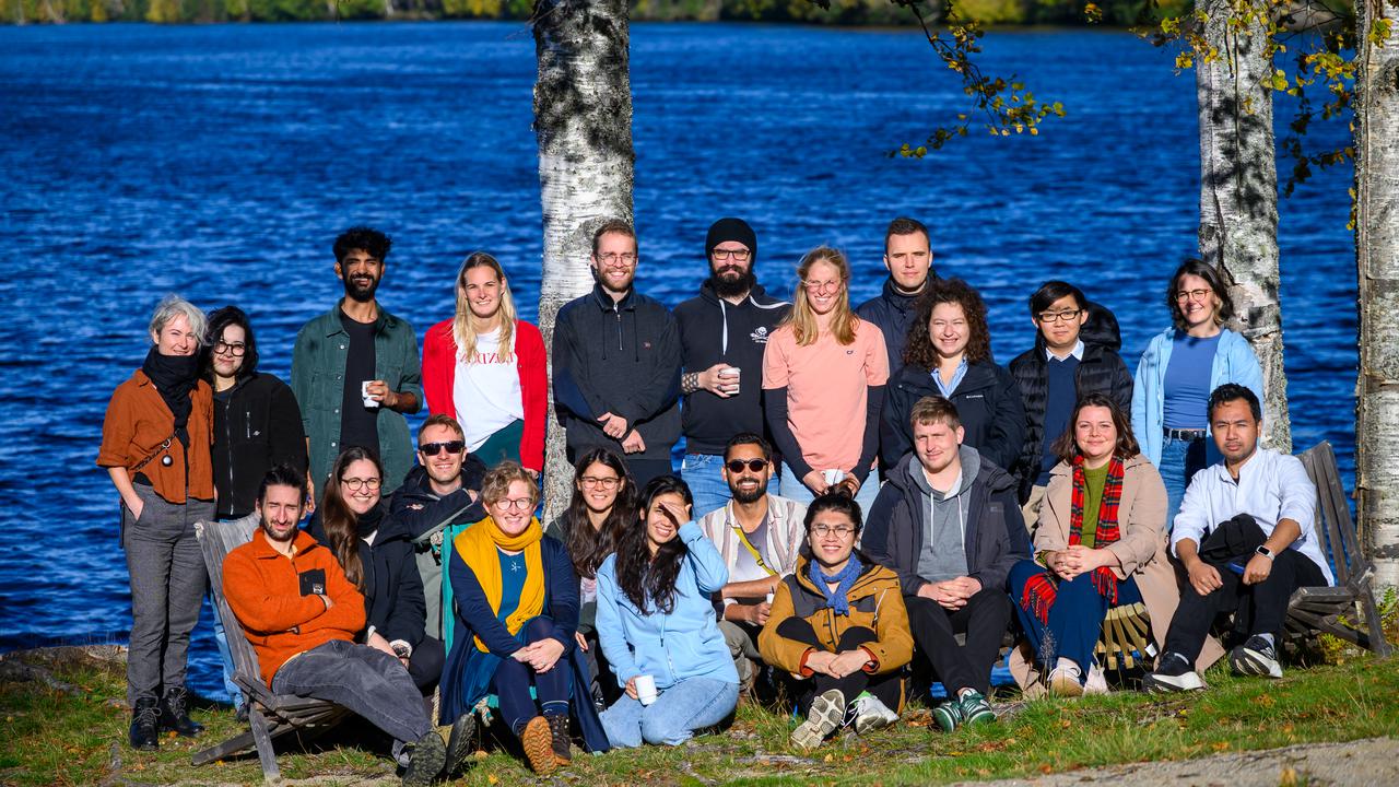 A group of people standing next to each other near a river.