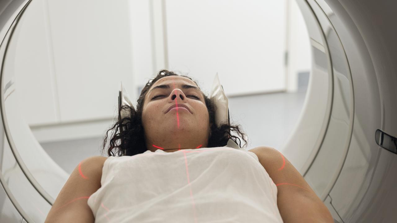 Kvinna med hörlurar ligger i MR-kamera