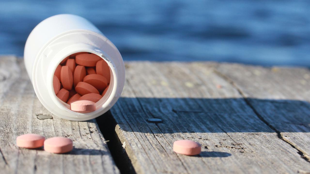 Öppnad vält burk med medicintabletter som ramlat ut på en brygga.