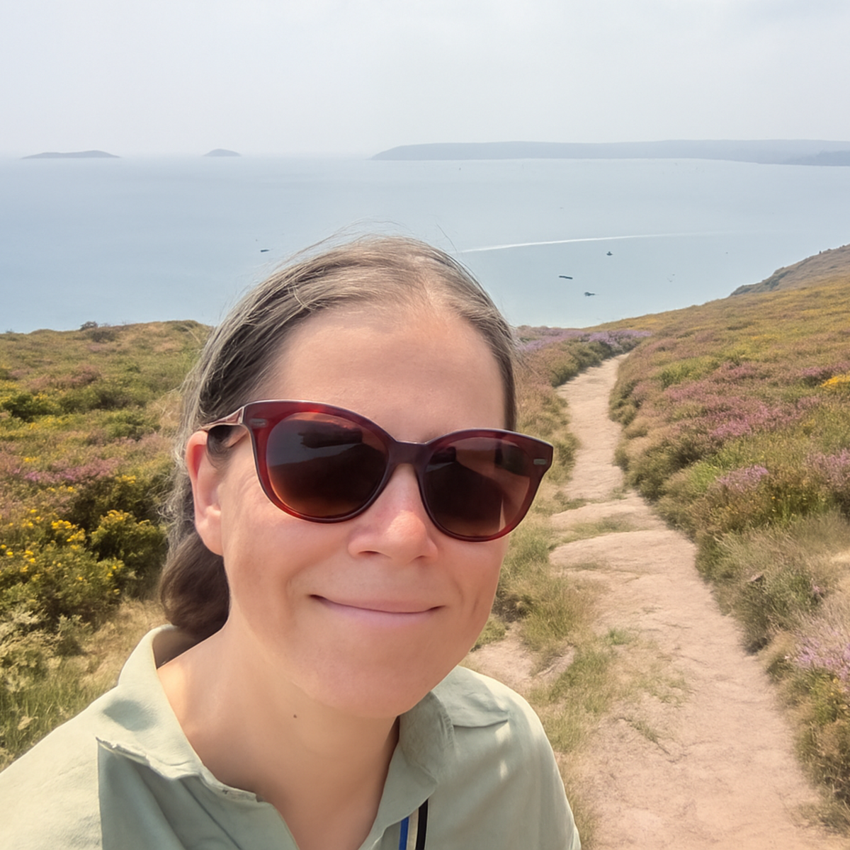 Porträttbild i naturskön miljö med havet i bakgrunden.