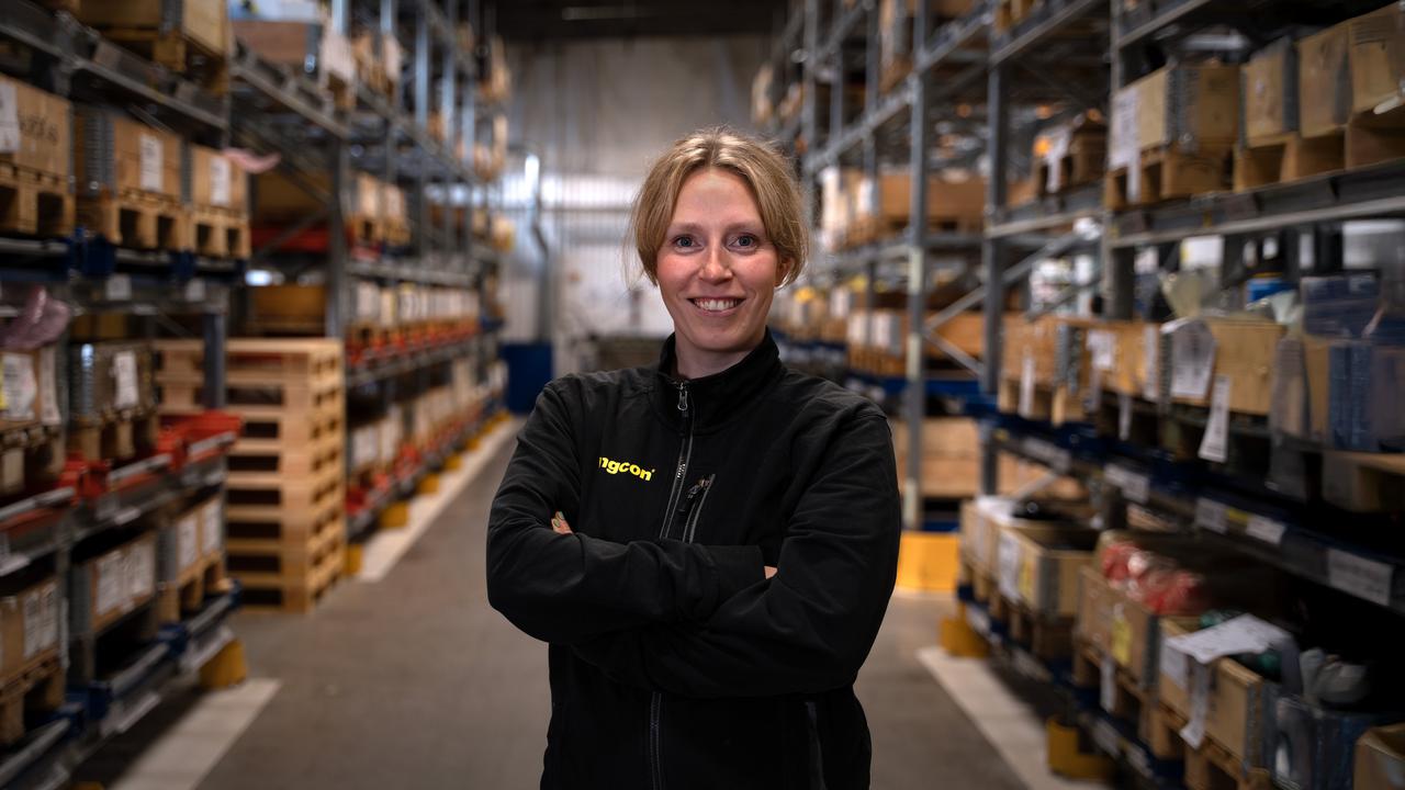 En kvinna som står i en lagerlokal med många hyllor.