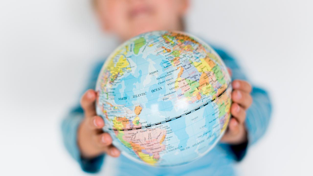 Barn håller upp en liten jordglob mellan sina händer.