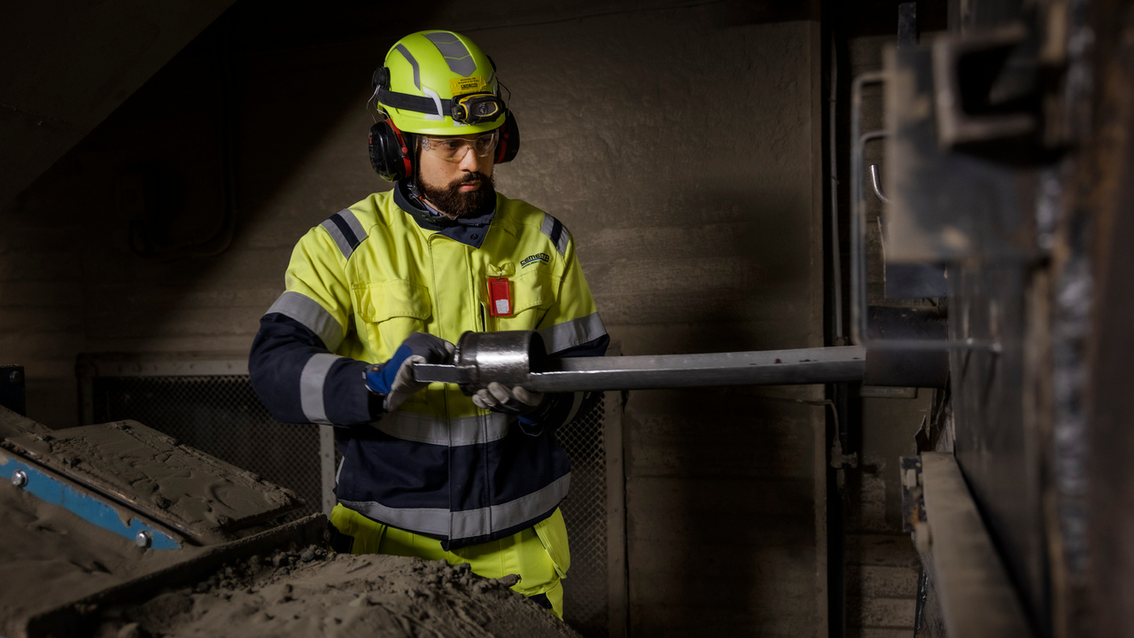 En man i gula arbetskläder arbetar på en maskin