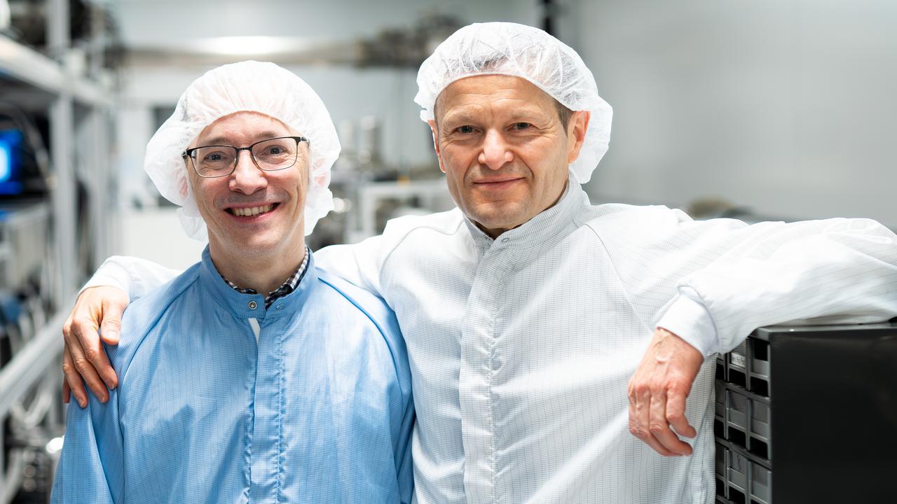 Två män i skyddskläder och skyddsmössa står brevid varandra. Ferenc håller armen om László.