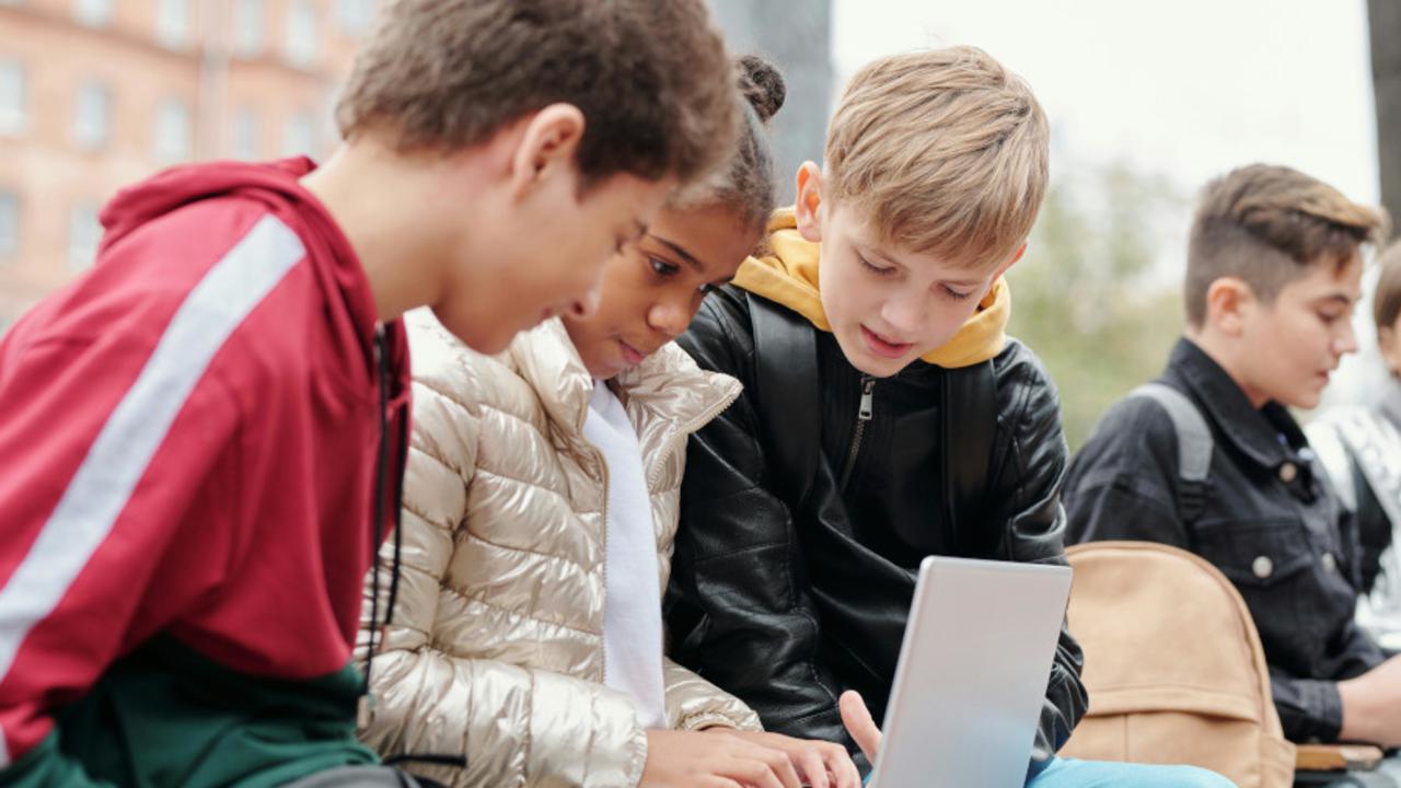 Barn utomhus tittar på en laptop