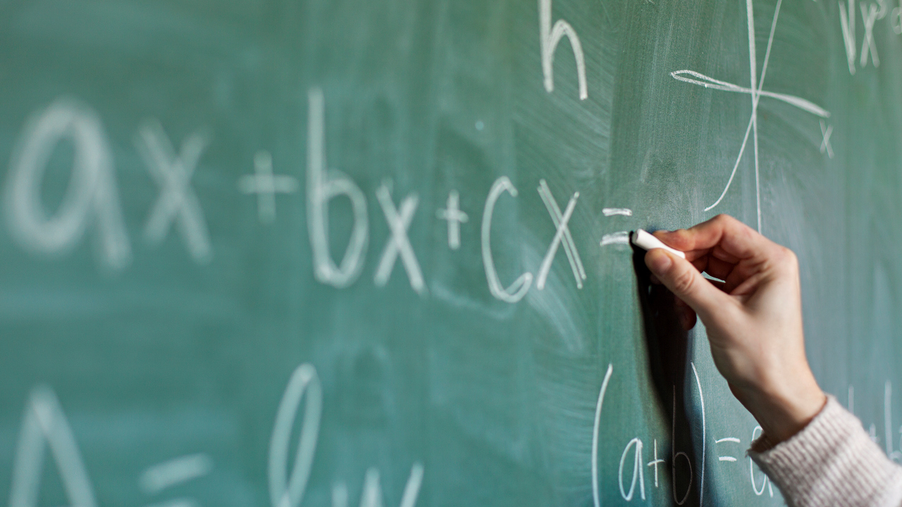 Bild på hand som skriver mattetal på grön tavla