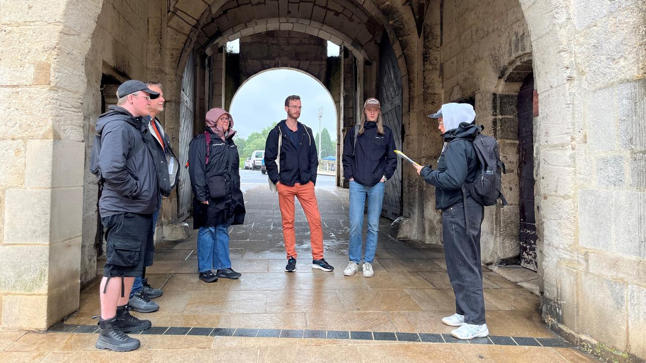 6 personer står under en valvbåge till en stenbyggnad