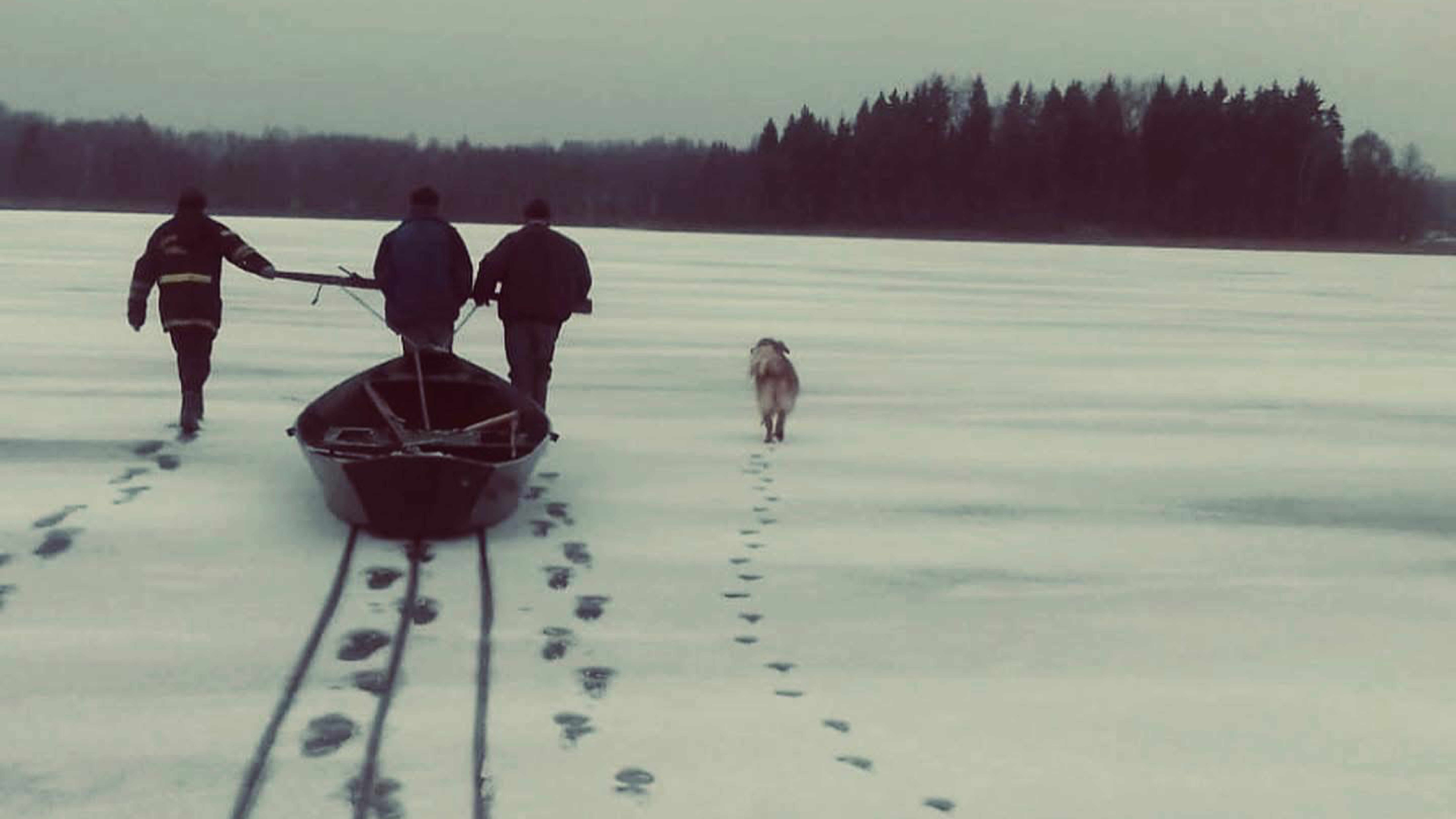 People walking over an ice and pulling a boat.