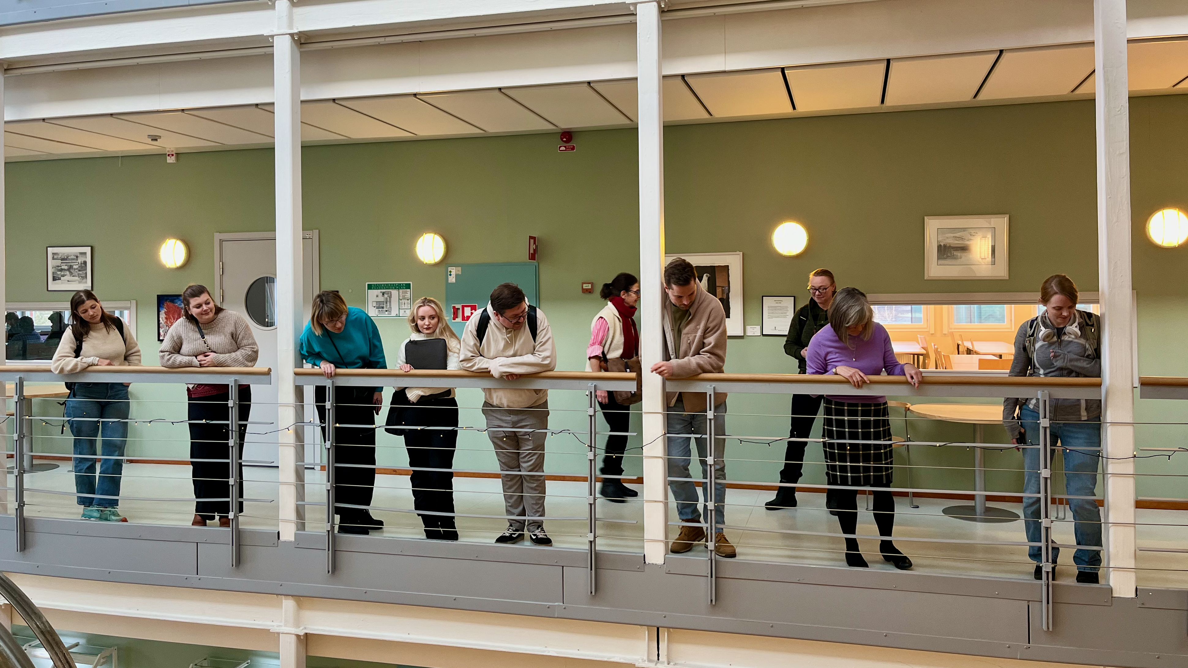 Doktorandskolans doktorander står vid räcket på IRF och tittar ner på det guiden visar dem