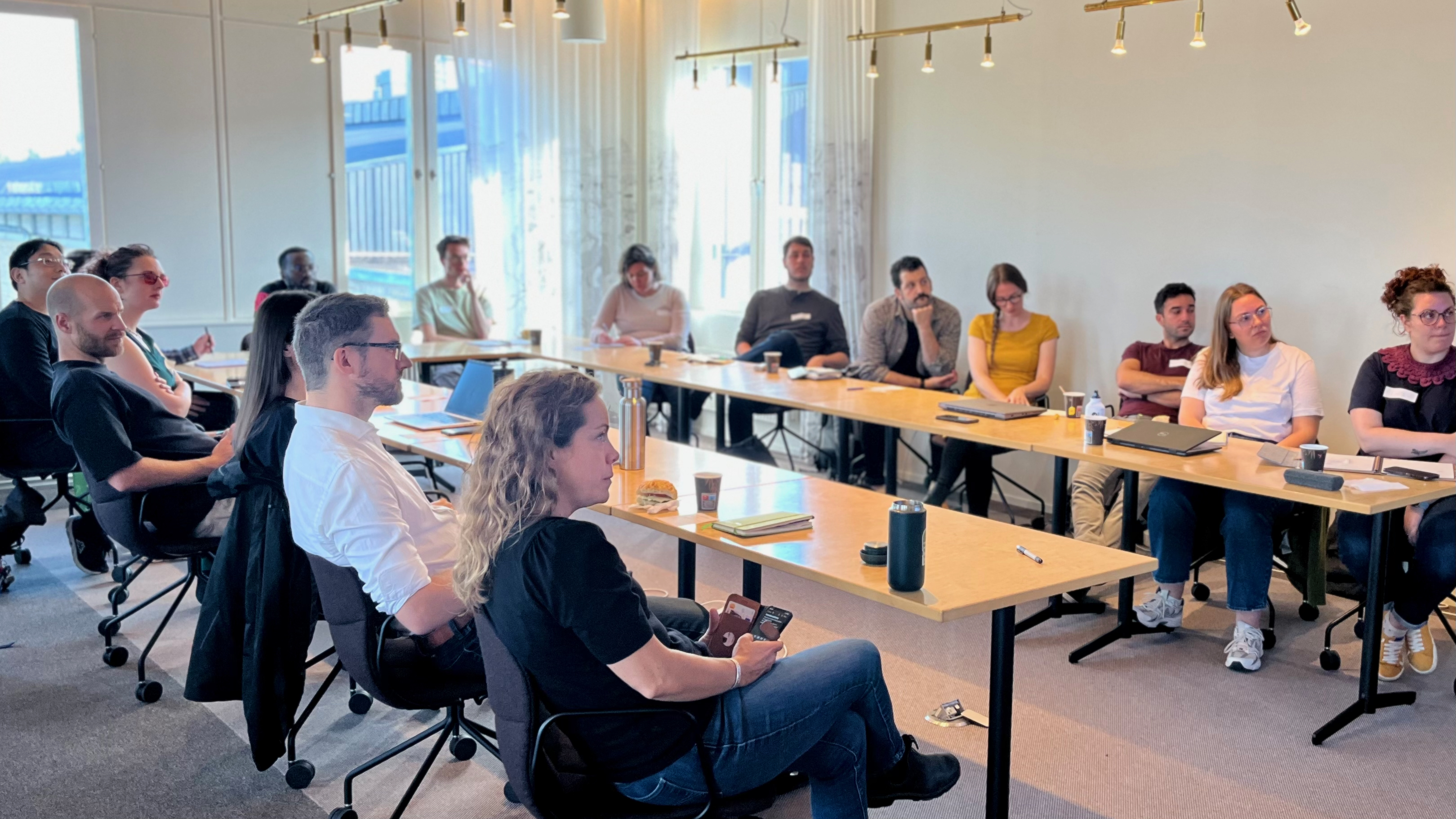 Deltagarna ta del av föreläsningar runt ett U-format bord med blicken på presentatören