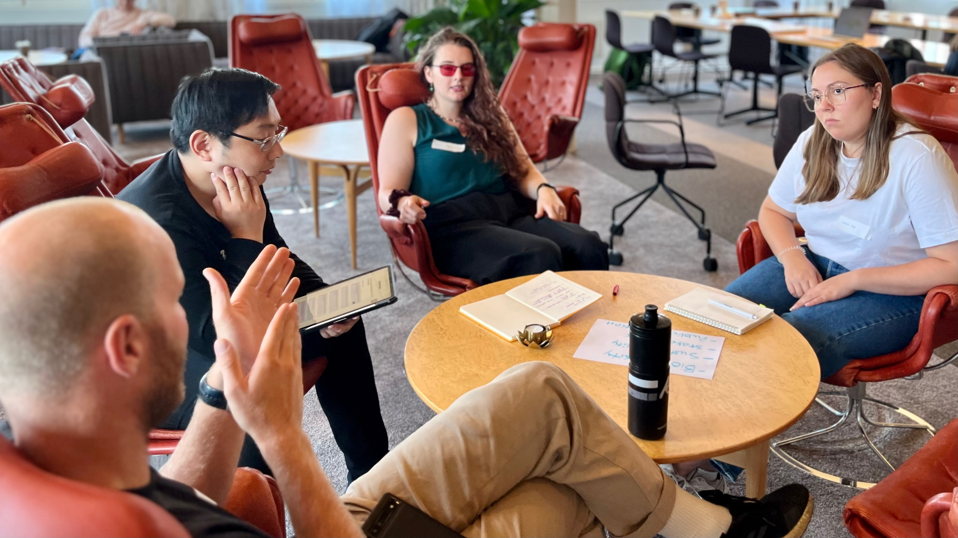 4 personer runt ett bord som pratar med varandra och gestikulerar