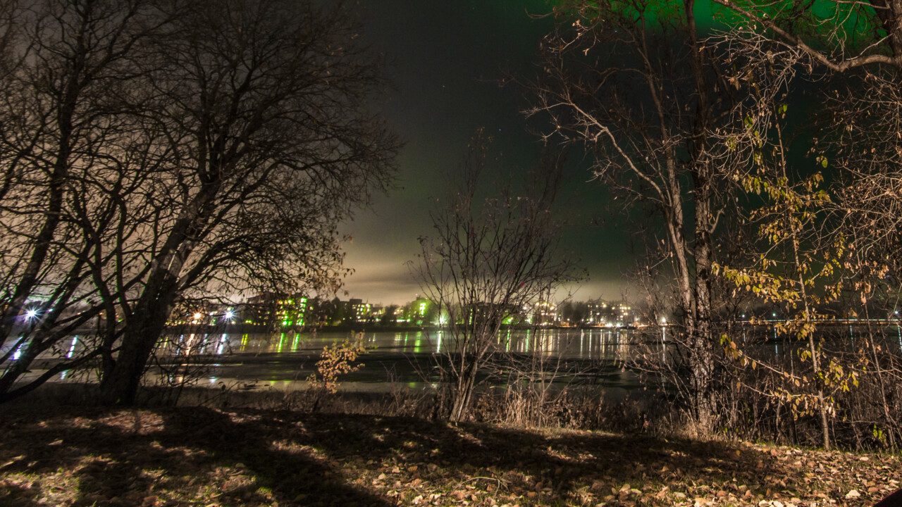 Person som sitter ute och betraktar norrskenet.