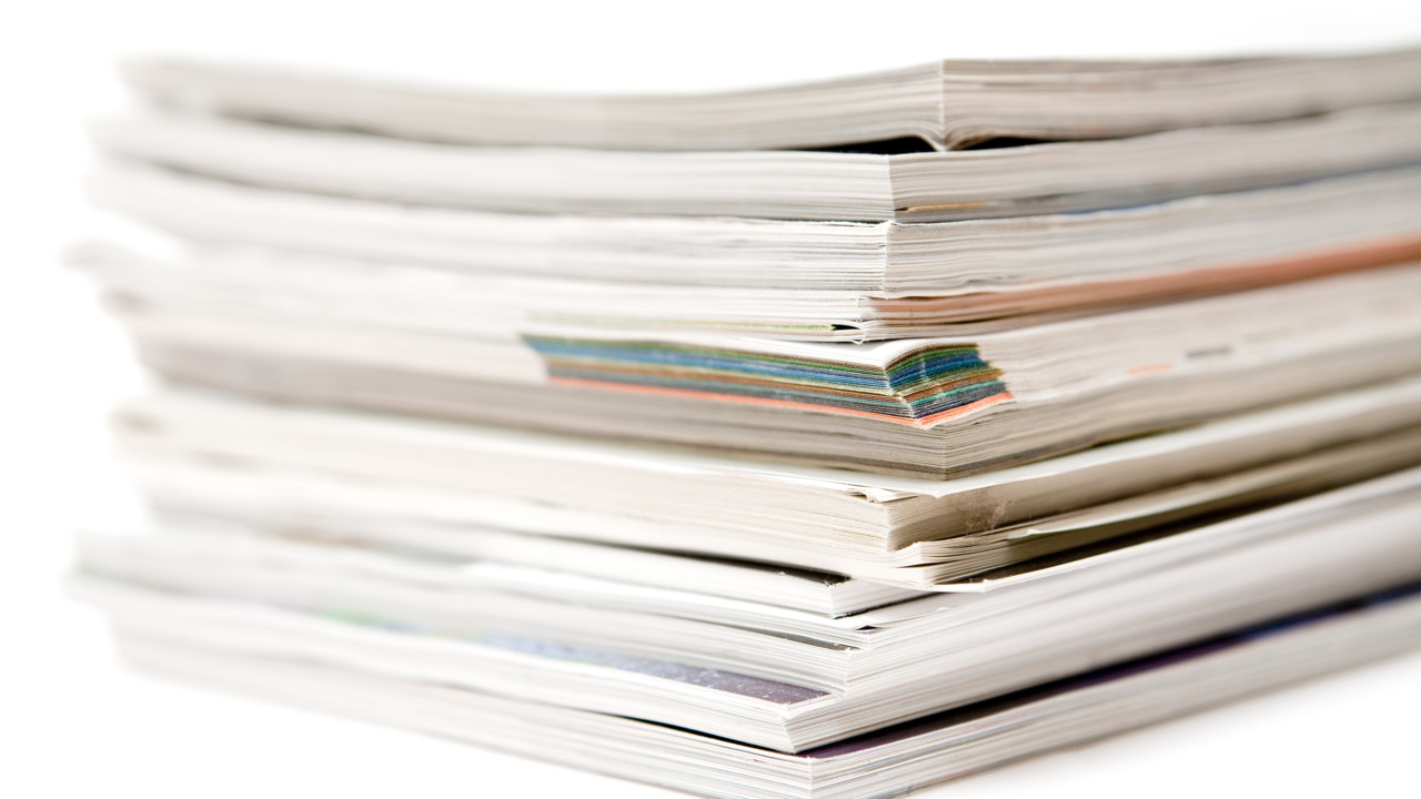 En trave med tidskrifter mot en vit bakgrund