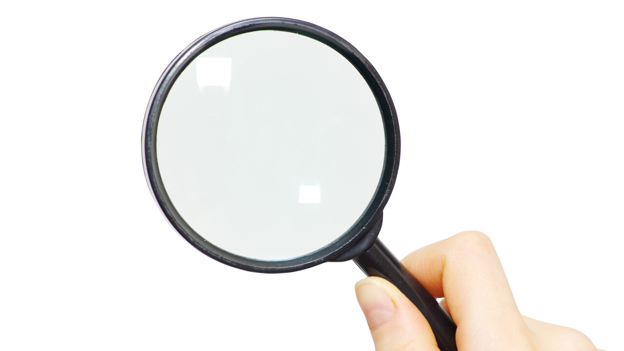 Hand håller i ett förstoringsglas.