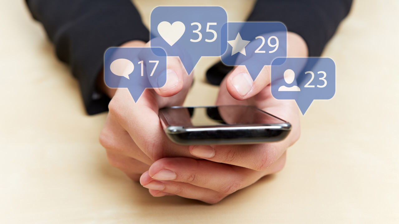 Händer som håller i mobil och hålle på med sociala medier. Inlagda pratbubblor med aviseringar.