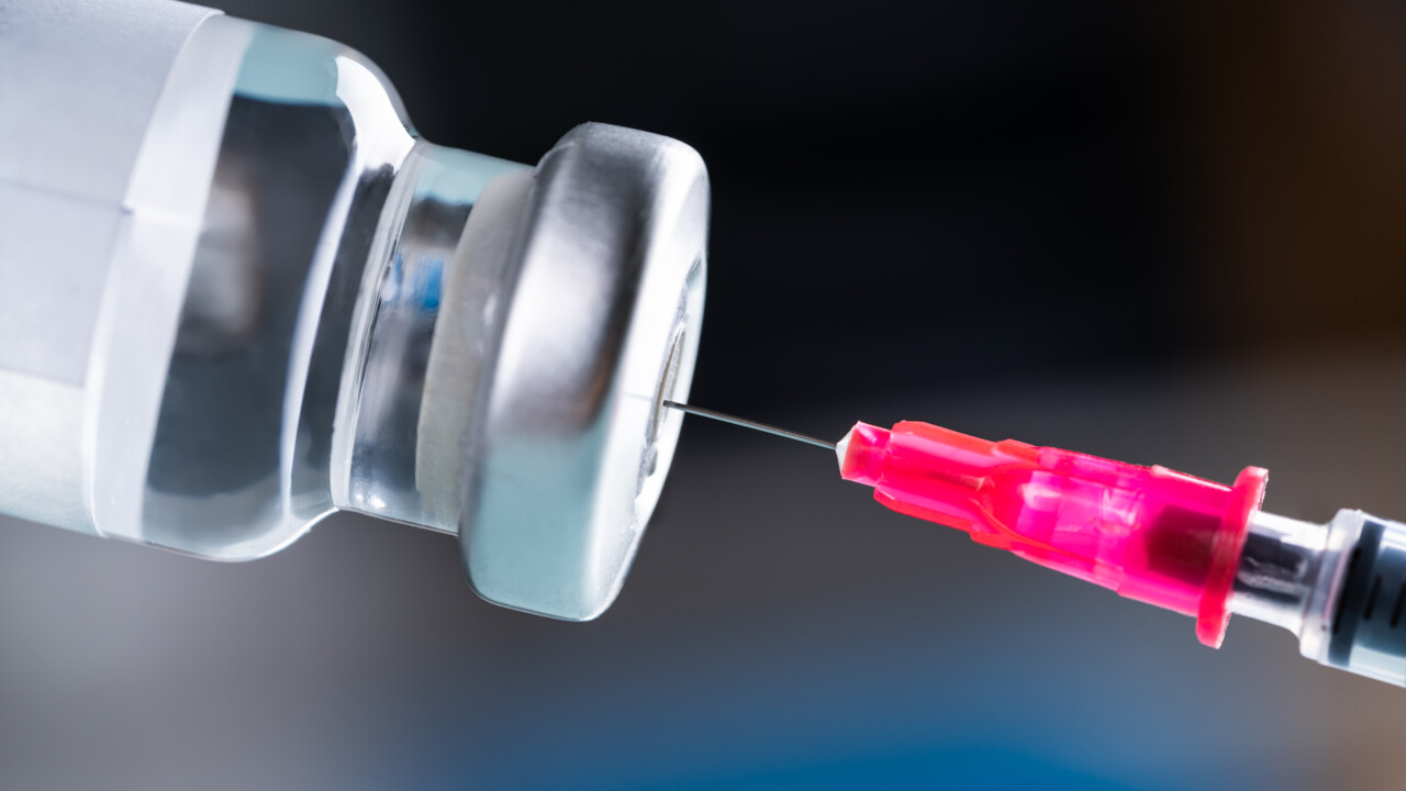 Nål som sticks in i behållare med vaccin.