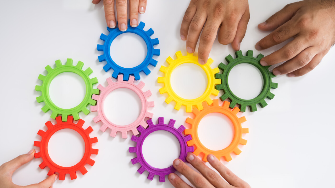 Händer som pusslar ihop färgglada kugghjul