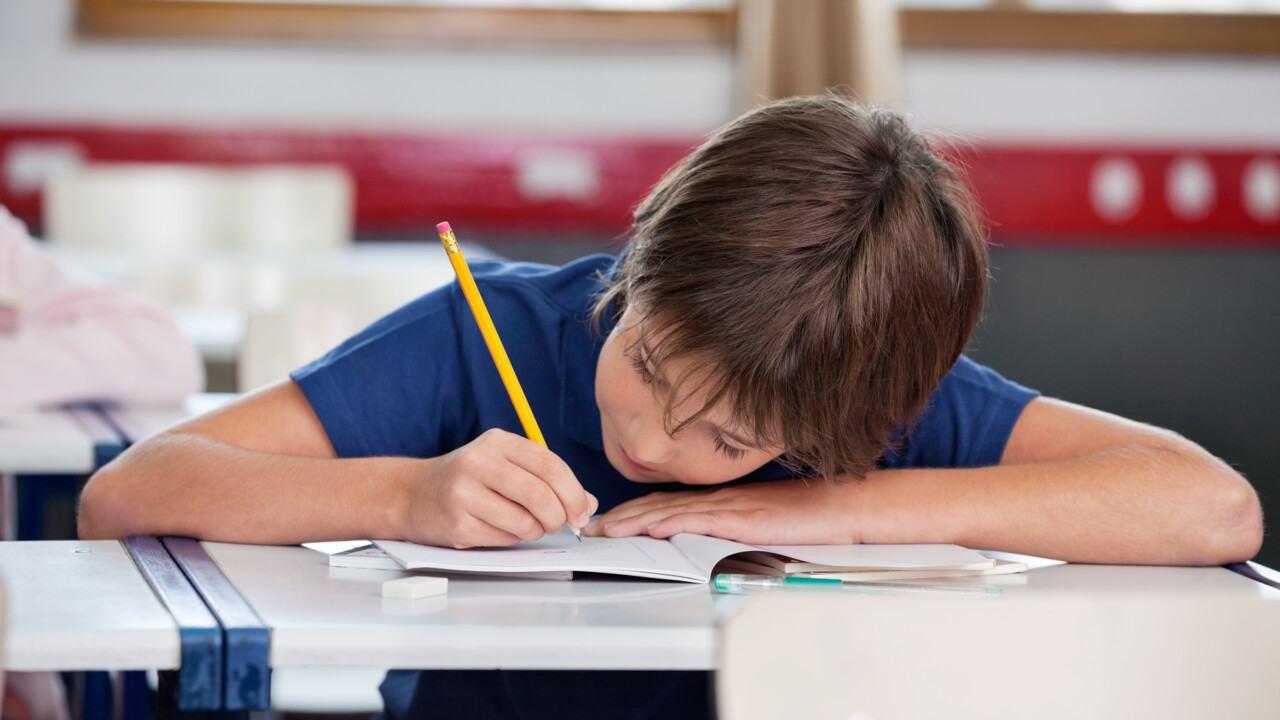 Skolbarn som skriver i ett häfte 