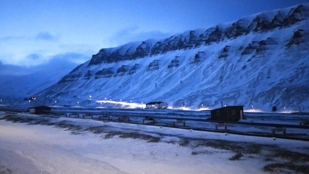 Snöiga berg i Svalbard, i gryningsljus