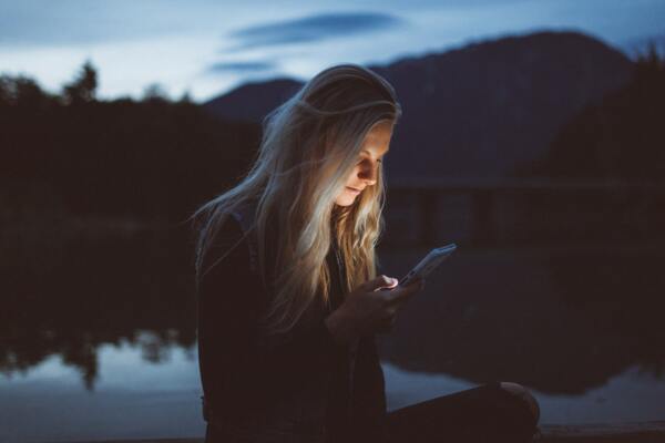 Woman by a lake holding smartphone