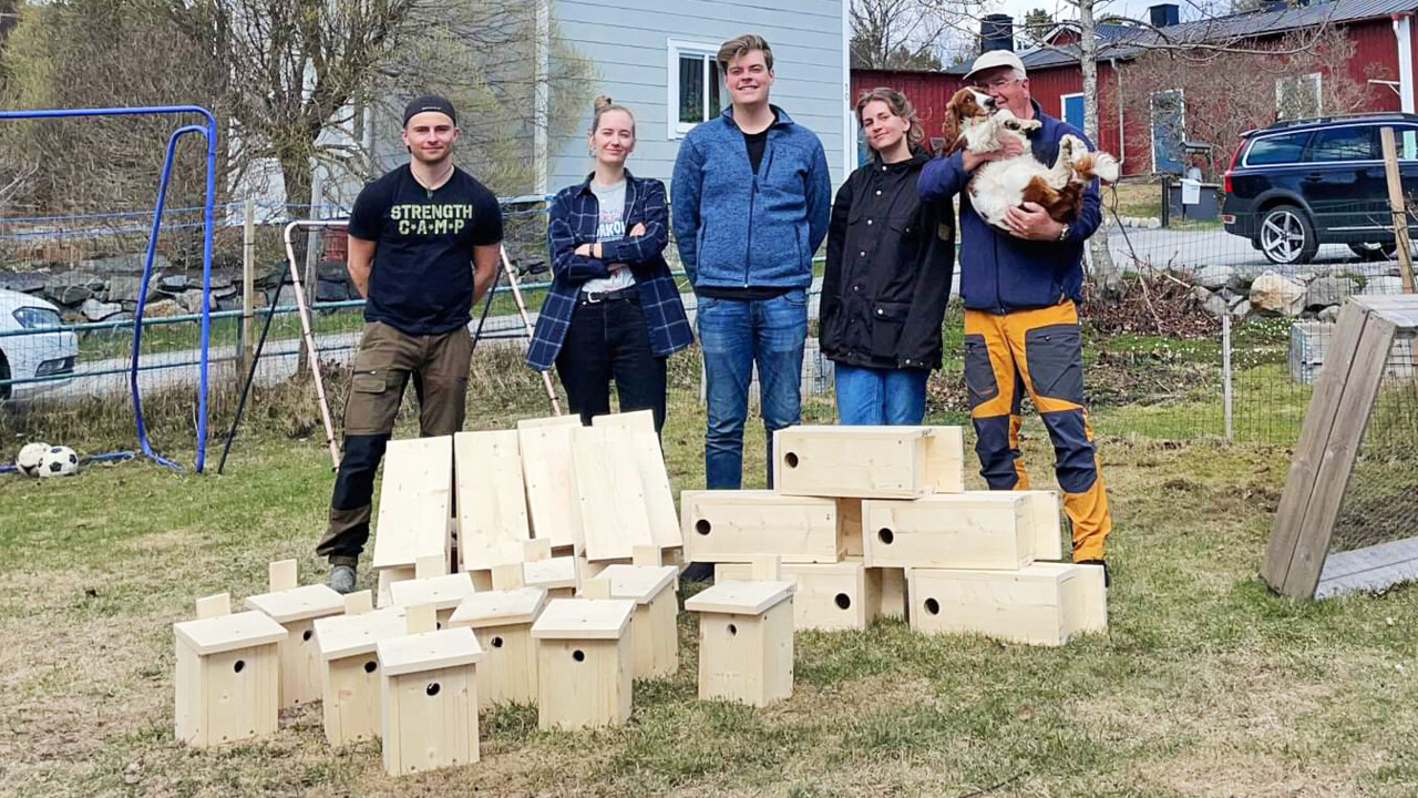 Gruppbild på fyra studenter och en lärare som står bakom fågelholkar de byggt för biologiska mångfaldens dag.