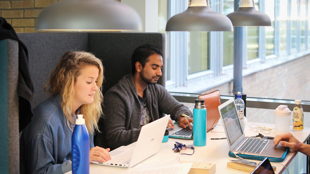 Students with laptops studiing at a table at Umeå University