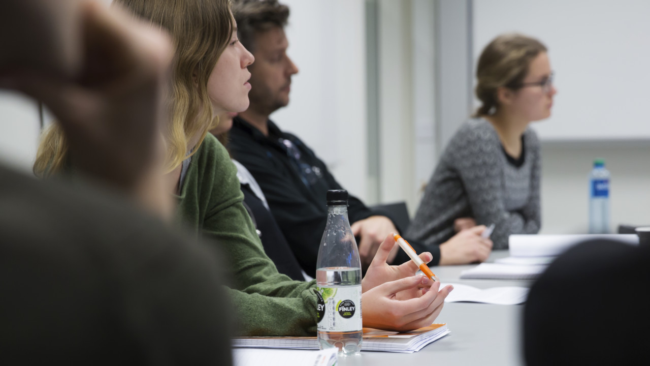 Flera idéhistoriestudenter sitter vid ett bord och lyssnar vid ett seminarium