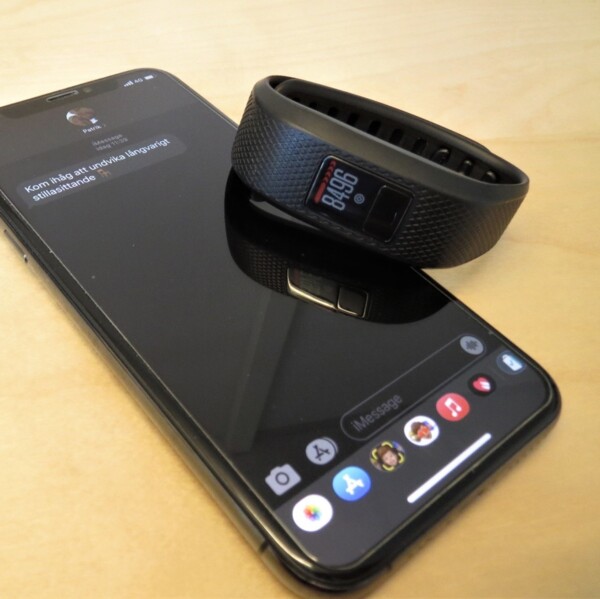 Mobiltelefon och aktivitetsband med appen mHealth öppen