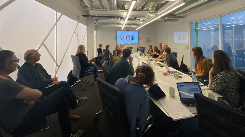 Ett konferensbord med människor som lyssnar på Mikaela Wikströms presentation