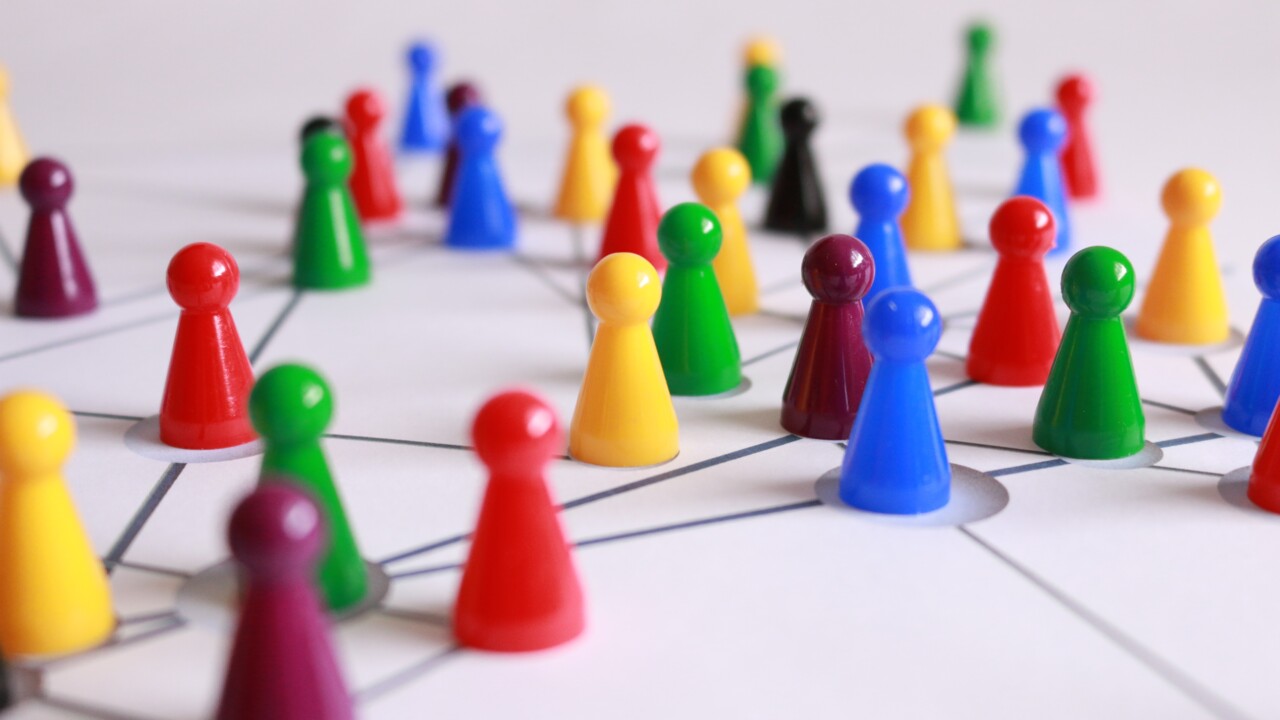 Olikfärgade spelpjäser i plast placerade på ett underlag med markeringar för att illustrera nätverk.