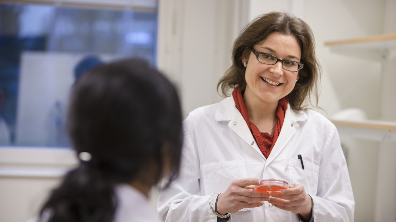 Andrea Puhar i vit labbrock samtalar med en kollega.