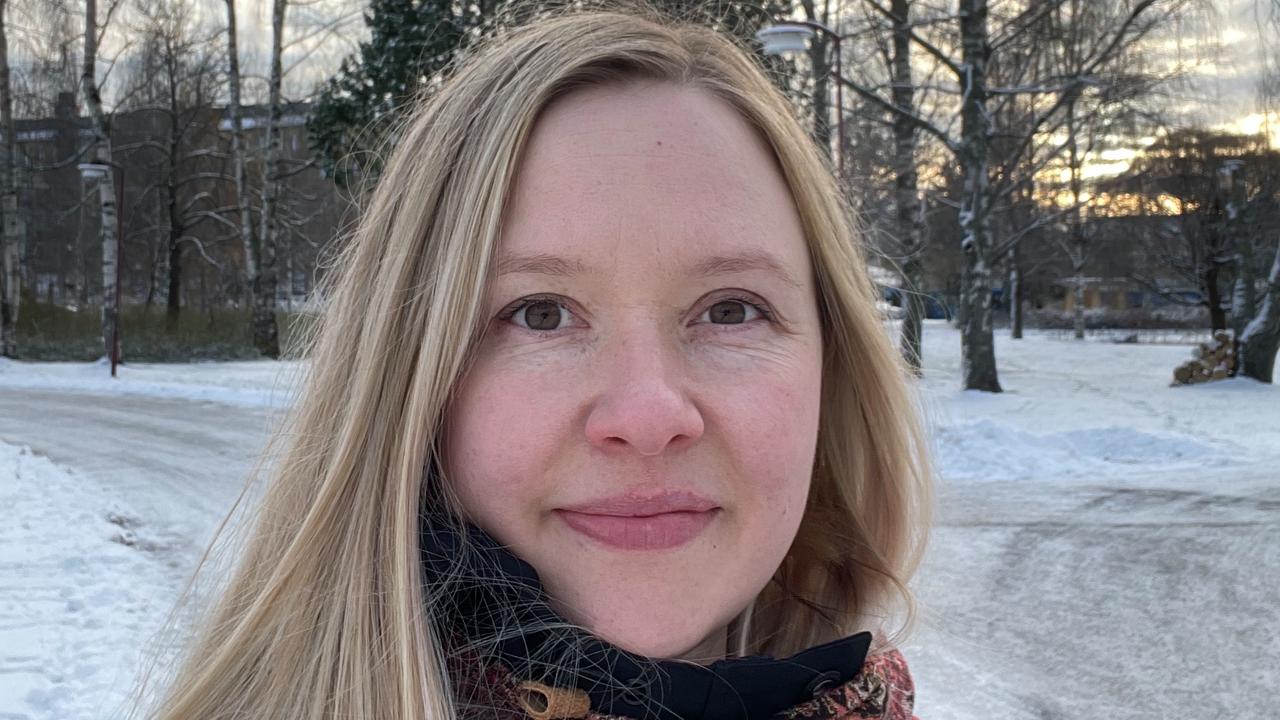 En kvinna med långt blont hår står i snön.