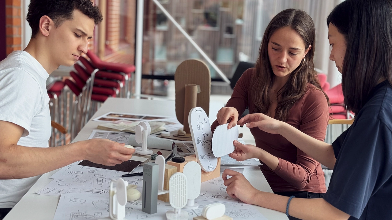 Photo of three master's students working on protypes on a table