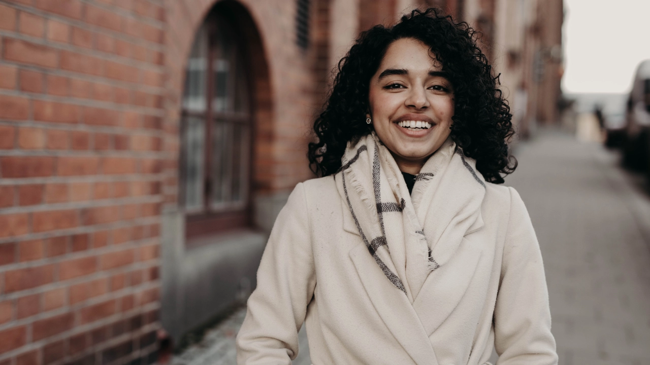 Kvinna utomhus ler och tittar in i kameran. 