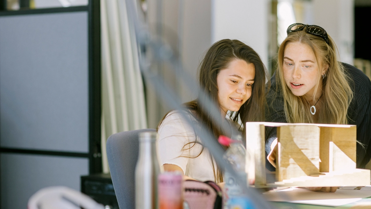 Två tjejer tittar på ett projekt.